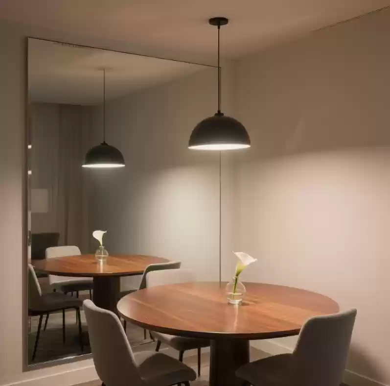 Sala de Jantar Compacta Com um Grande Espelho em Uma Das Paredes Refletindo a Mesa e a Iluminacao